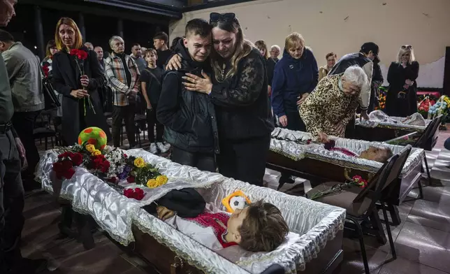 Friends come to pay last respects to the family, Maksym Martynenko, 11, Natalia Martynenko, 49, and Mykola Martynenko, 41, killed in a deadly Palm Sunday Russian attack on Sumy on April 13, during farewell ceremony in Sumy, Ukraine, Wednesday, April 16, 2025. (AP Photo/Evgeniy Maloletka)
