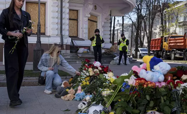 Women put flowers on a site of a Russian missile strike in Sumy, Ukraine, April 15, 2025. (AP Photo/Evgeniy Maloletka)