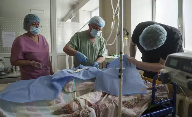 Dr. Oleksandr Zaitsev treats a patient injured in a deadly Palm Sunday Russian attack on Sumy on April 13, at a hospital ICU in Sumy, Ukraine, Tuesday, April 15, 2025. (AP Photo/Evgeniy Maloletka)