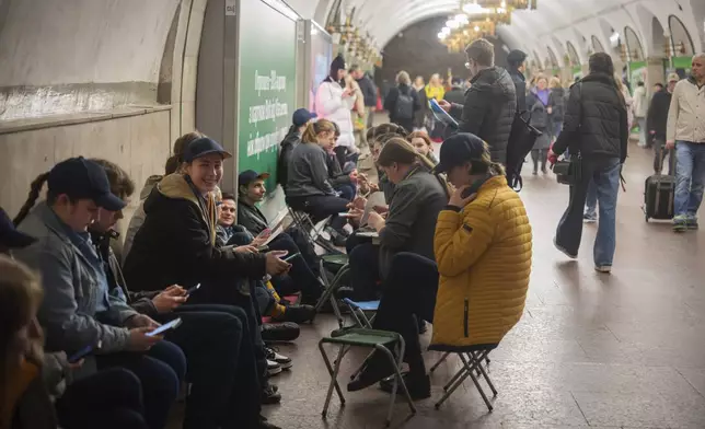 Schoolchildren do their homework and people hide in an underground metro station following air raid sirens alerting of a Russian missile attack in Kyiv, Ukraine, Wednesday, April 16, 2025. (AP Photo/Efrem Lukatsky)