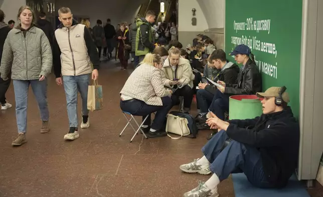 Schoolchildren do their homework and people hide in an underground metro station following air raid sirens alerting of a Russian missile attack in Kyiv, Ukraine, Wednesday, April 16, 2025. (AP Photo/Efrem Lukatsky)