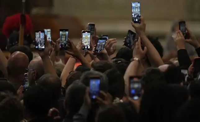 Faithful take photos as they pay their respects to Pope Francis inside St. Peter's Basilica at the Vatican, Wednesday, April 23, 2025, where his body will lie in state for three days. (AP Photo/Gregorio Borgia)