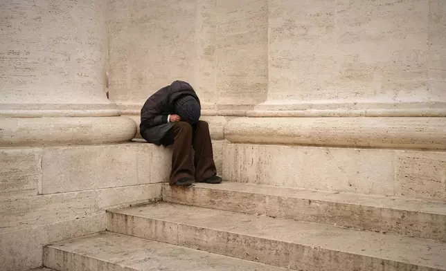 A woman sits in St. Peter's Square as people wait to pay their respects to the late Pope Francis, who will lie in state at St. Peter's Basilica for three days, at the Vatican, Wednesday, April 23, 2025. (AP Photo/Andreea Alexandru)