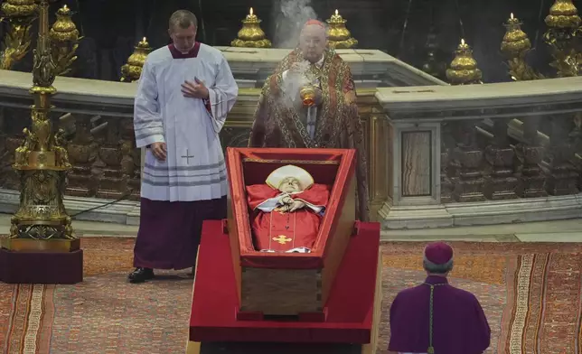 Cardinal Camerlengo Kevin Joseph Farrell asperges incense around the body of Pope Francis inside St. Peter's Basilica at the Vatican, Wednesday, April 23, 2025, where he will lie in state for three days. (AP Photo/Andrew Medichini, Pool)