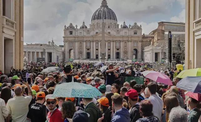 A volunteer, center, gives directions to the crowd waiting to enter St. Peter's Basilica where Pope Francis is lying in state, at the Vatican, Friday, April 25, 2025. (AP Photo/Markus Schreiber)