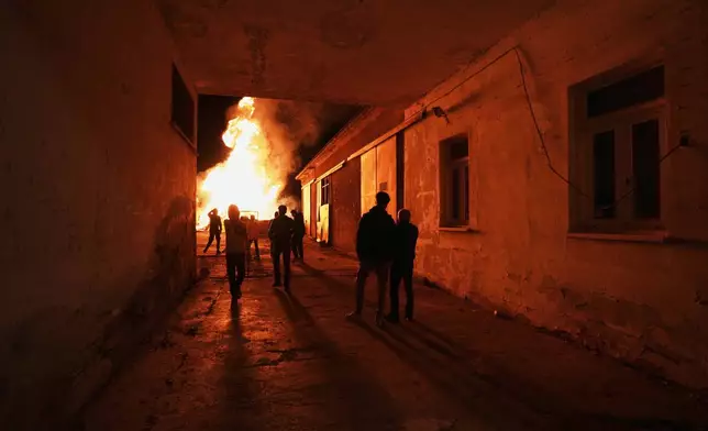 Youth stand in front of the traditional Easter bonfire, or lambratzia, where effigies of Judas Iscariot, the disciple believed to have betrayed Jesus, are burned during Easter celebrations at the church of Agios Epifanios in the village of Droushia in the Paphos district on the Akamas peninsula on holy Saturday, April 19, 2025, in Cyprus. (AP Photo/Petros Karadjias)