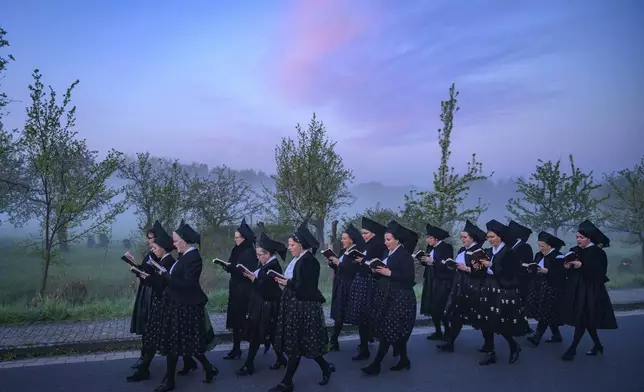 Women in black church costumes sing Easter hymns as they walk through the small Lusatian village of Maust near Cottbus Sunday, April 20, 2025. (Patrick Pleul/dpa/dpa via AP)