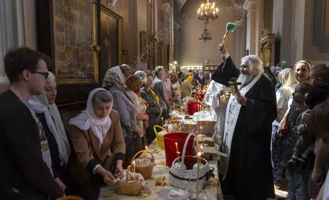 A Lithuanian Orthodox priest blesses cakes and Easter eggs during an Orthodox Easter ceremony at the Orthodox Church of the Holy Spirit in Vilnius, Lithuania, Saturday, April 19, 2025. (AP Photo/Mindaugas Kulbis)