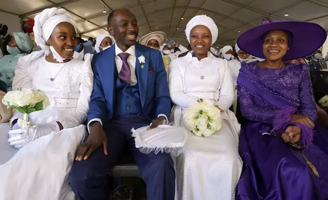 A man with his wife and two of his brides sits inside a marquee ahead of the mass Easter weddings for 3,000 people, some polygamous, at the International Pentecost Holiness Church in Heidelberg, east of Johannesburg, South Africa, Sunday, April 20, 2025. (AP Photo/Themba Hadebe)