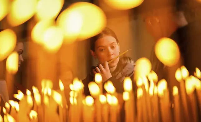 A Christian Orthodox worshipper lights candles during the Easter Sunday Resurrection liturgy, marking the end of the Holy Week at the Patriarchal Church of St. George in Istanbul, Turkey, Sunday, April 20, 2025. (AP Photo/Emrah Gurel)