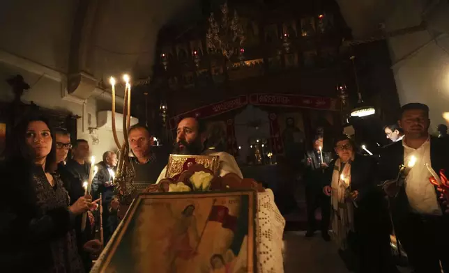 A Christian Orthodox priest takes the holy light at the Agios Epifanios church during Easter celebrations in Droushia in the Paphos district on the Akamas peninsula of Cyprus, early Sunday, April 20, 2025. (AP Photo/Petros Karadjias)