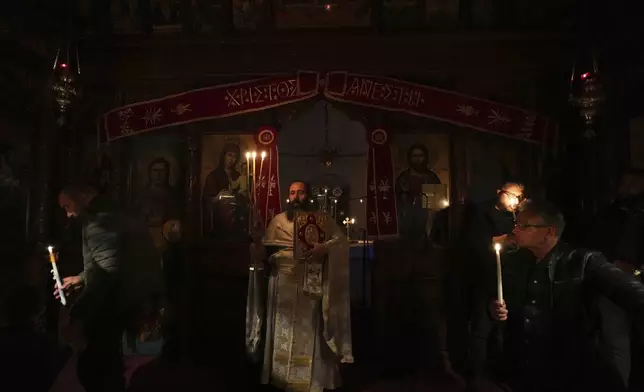 A Christian Orthodox priest takes the holy light at the Agios Epifanios church during Easter celebrations in Droushia in the Paphos district on the Akamas peninsula of Cyprus, early Sunday, April 20, 2025. (AP Photo/Petros Karadjias)