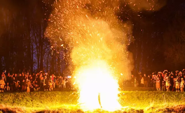 Members of the Dechenverein Lügde ignite the straw in a wooden wheel, which then rolls down a slope on fire during Easter celebrations in Lügde, Germany, on Sunday, April 20, 2025. (Christoph Reichwein/dpa via AP)