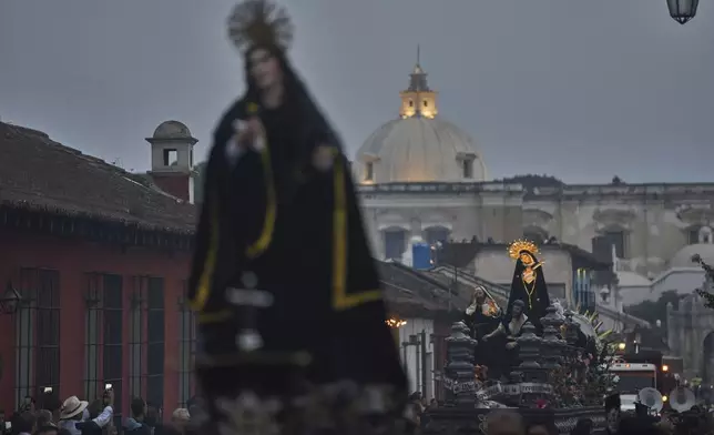 Devotees carry a religious float with a statue of the Virgin of Solitude, in background, right center, commemorating the death of Jesus Christ at Calvary, during a Holy Week procession in Antigua, Guatemala, on Holy Saturday, April 19, 2025. (AP Photo/Moises Castillo)