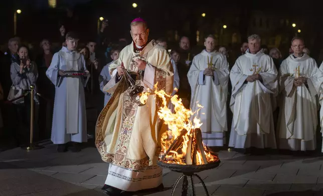 Archbishop Gintaras Grusas performs the blessing during the Easter vigil Mass at the Cathedral in Vilnius, Lithuania, late Saturday, April 19, 2025. (AP Photo/Mindaugas Kulbis)