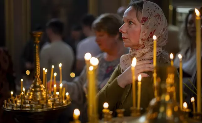 Believers pray during the cake and Easter egg blessing ceremony at the Orthodox Church of the Holy Spirit in Vilnius, Lithuania, Saturday, April 19, 2025. (AP Photo/Mindaugas Kulbis)