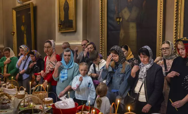 Believers pray during the cake and Easter egg blessing ceremony at the Orthodox Church of the Holy Spirit in Vilnius, Lithuania, Saturday, April 19, 2025. (AP Photo/Mindaugas Kulbis)