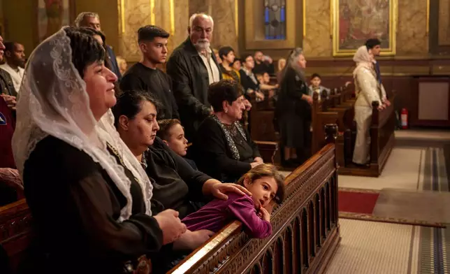 A child rests her head on a pew frontal during the Orthodox Easter service at the Armenian cathedral in Bucharest, Romania, Saturday, April 19, 2025. (AP Photo/Andreea Alexandru)