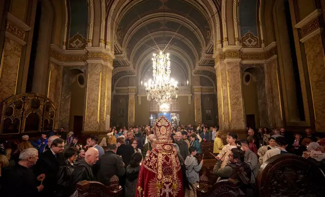 Iraq-born Armenian church Archbishop Datev Hagopian shares the holy light during the Orthodox Easter service at the Armenian cathedral in Bucharest, Romania, Saturday, April 19, 2025. (AP Photo/Andreea Alexandru)