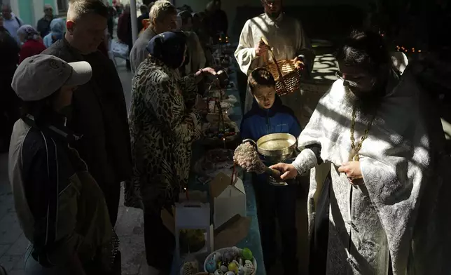 Father Konstantin, right, blesses traditional Easter cakes and painted eggs in preparation for Easter celebrations outside of the Epiphany Cathedral at Yelokhovo on Great Holy Saturday in Moscow, Russia, Saturday, April 19, 2025. (AP Photo/Pavel Bednyakov)