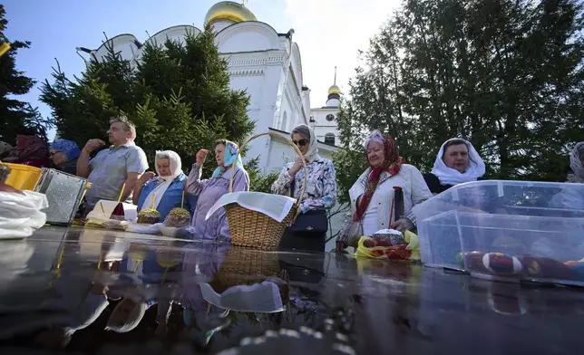 Believers with their baskets containing traditional cakes and painted eggs cross themselves as they wait to be blessed by a Russian Orthodox priest, in preparation for an Easter celebration at the St. Boris and Gleb Monastery in the old Russian town of Dmitrov, some 70 km (44 miles) north of Moscow, Russia, Saturday, April 19, 2025. (AP Photo/Alexander Zemlianichenko)