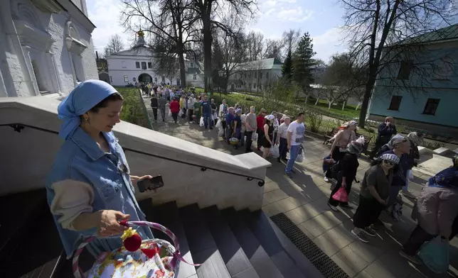 Believers with their baskets and bags containing traditional cakes and painted eggs lineup to be blessed by a Russian Orthodox priest, in preparation for an Easter celebration at the St. Boris and Gleb Monastery in the old Russian town of Dmitrov, some 70 km (44 miles) north of Moscow, Russia, Saturday, April 19, 2025. (AP Photo/Alexander Zemlianichenko)