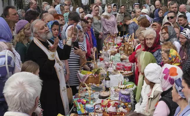 An Orthodox priest delivers a sermon to the faithful prior to blessing traditional Easter cakes and painted eggs prepared for Easter celebration at a church in St. Petersburg, Russia, Saturday, April 19, 2025. (AP Photo/Dmitri Lovetsky)