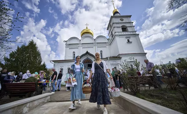 Two young women carry their baskets containing traditional cakes and painted eggs as Believers wait to be blessed by a Russian Orthodox priest, in preparation for an Easter celebration at the St. Boris and Gleb Monastery in the old Russian town of Dmitrov, some 70 km (44 miles) north of Moscow, Russia, Saturday, April 19, 2025. (AP Photo/Alexander Zemlianichenko)