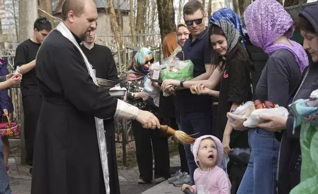 An Orthodox priest blesses believers and their traditional Easter cakes and painted eggs prepared for Easter celebration at a church in St. Petersburg, Russia, Saturday, April 19, 2025. (AP Photo/Dmitri Lovetsky)