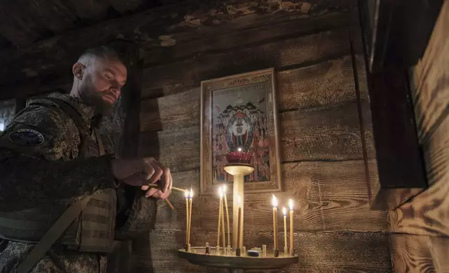 In this photo taken from video distributed by Russian Defense Ministry Press Service on Sunday, April 20, 2025, a Russian soldier lights a candle attending a religion service on eve of Orthodox Easter at an unspecified location in Ukraine. (Russian Defense Ministry Press Service via AP)