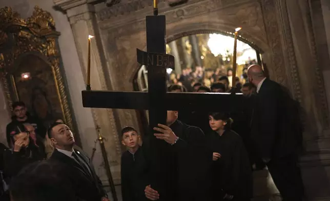 A Christian Orthodox worshipper carries a wooden cross during the service of the Graveside Lamentation at the Patriarchal Church of St. George, in Istanbul, Turkey, Friday, April 18, 2025. (AP Photo/Francisco Seco)
