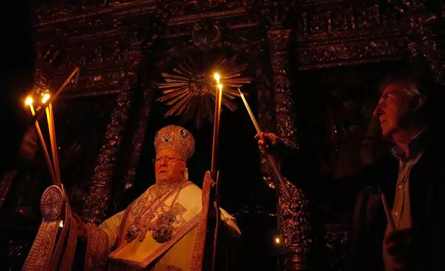 Ecumenical Patriarch Bartholomew I, left, the spiritual leader of the world's Eastern Orthodox Christians, holds candles as he conducts the Easter Vigil Mass on the eve of Christ's resurrection at the Patriarchal Church of St. George in Istanbul, Turkey, Sunday, April 20, 2025. (AP Photo/Khalil Hamra)