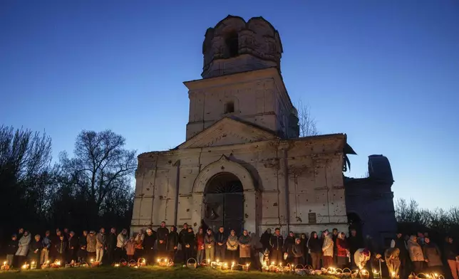 People stand in line to have their Easter baskets blessed in front of a church destroyed in fighting between Russian and Ukrainian forces, during celebration of the Orthodox Easter in Lukashivka village, Ukraine, on Sunday, April 20, 2025. (AP Photo/Evgeniy Maloletka)