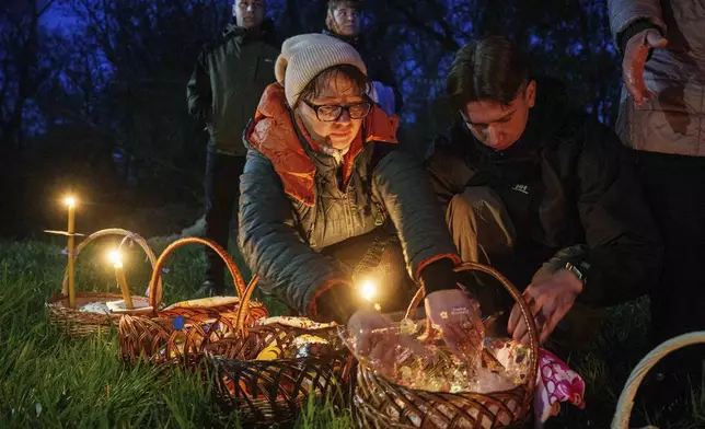 People prepare their Easter baskets to be blessed in front of a church destroyed in fighting between Russian and Ukrainian forces, during celebration of the Orthodox Easter in Lukashivka village, Ukraine, on Sunday, April 20, 2025. (AP Photo/Evgeniy Maloletka)