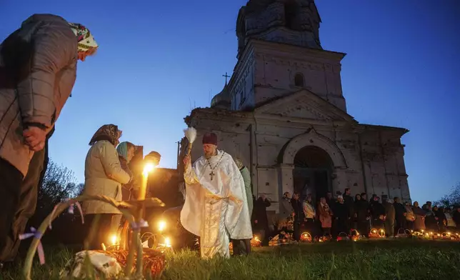 Priest Serhii Zezul blesses Easter baskets in front of a church destroyed in fighting between Russian and Ukrainian forces, during celebration of the Orthodox Easter in Lukashivka village, Ukraine, on Sunday, April 20, 2025. (AP Photo/Evgeniy Maloletka)
