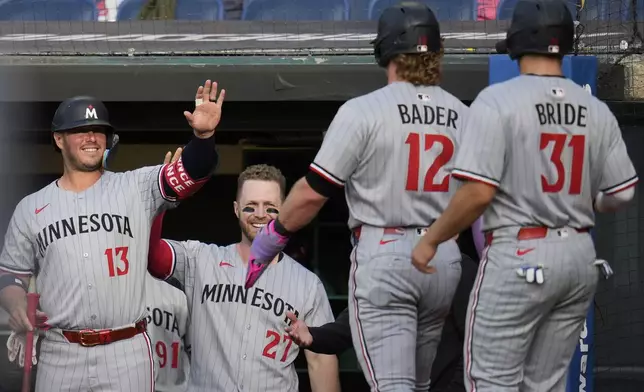 Minnesota Twins' Harrison Bader (12) and Jonah Bride (31) are greeted by teammates Ty France (13) and Ryan Jeffers (27) as they return to the dugout after scoring on a single hit by Byron Buxton in the second inning of a baseball game against the Cleveland Guardians in Cleveland, Monday, April 28, 2025. (AP Photo/Sue Ogrocki)