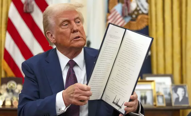 FILE - President Donald Trump holds up a signed executive order aiming to declassify remaining federal records relating to the assassinations of President John F. Kennedy, Sen. Robert F. Kennedy, and Martin Luther King Jr., in the Oval Office of the White House, Jan. 23, 2025, in Washington. (AP Photo/Ben Curtis, File)