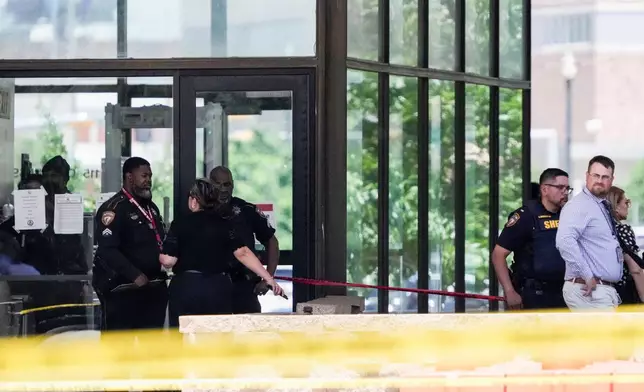 Law enforcement officers investigate the scene where a Harris County deputy and a suspect were shot outside the Family Law Center in Houston, Monday, April 21, 2025. (Brett Coomer/Houston Chronicle via AP)