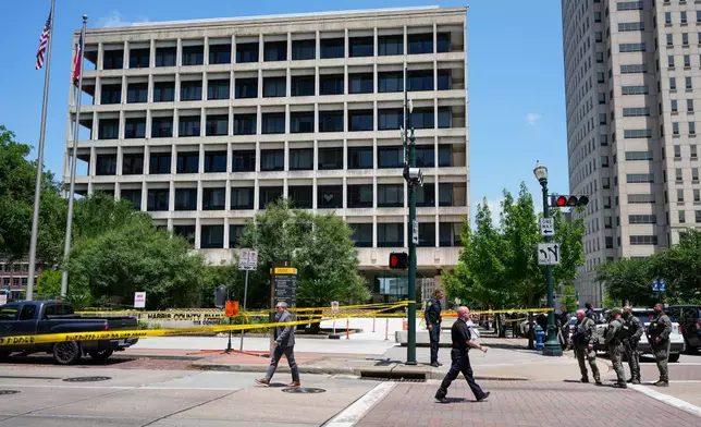 Law enforcement officers investigate the scene where a Harris County deputy and a suspect were shot near the courthouse complex in the 1100 block of Congress Street in Houston, Monday, April 21, 2025. (Brett Coomer/Houston Chronicle via AP)