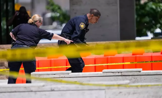 Law enforcement officers investigate the scene where a Harris County deputy and a suspect were shot outside The Family Law Center in Houston, Monday, April 21, 2025. (Brett Coomer/Houston Chronicle via AP)