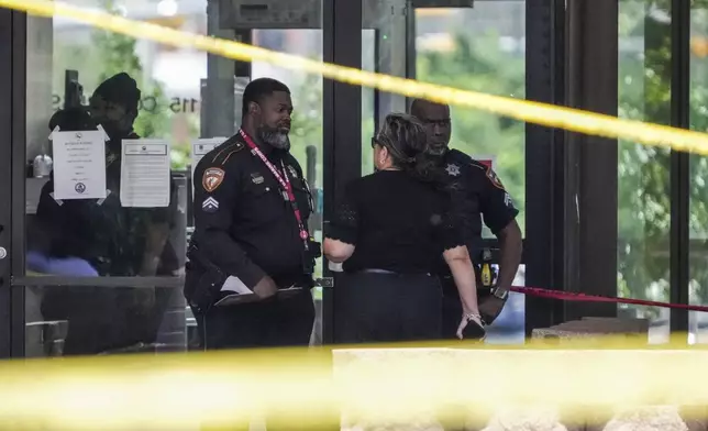 Law enforcement officers investigate the scene where a deputy and a suspect were shot near a courthouse complex in Houston, Monday, April 21, 2025. (Brett Coomer/Houston Chronicle via AP)