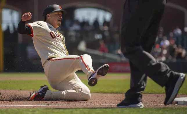 San Francisco Giants' Wilmer Flores slides into third base during the fifth inning of a baseball game against the Cincinnati Reds, Wednesday, April 9, 2025, in San Francisco. (AP Photo/Nic Coury)