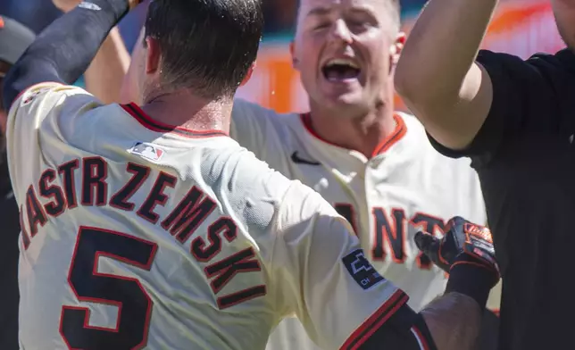 The San Francisco Giants celebrate a home run by Mike Yastrzemski (5) during the tenth inning of a baseball game to beat the Cincinnati Reds in San Francisco, Wednesday, April 9, 2025. (AP Photo/Nic Coury)