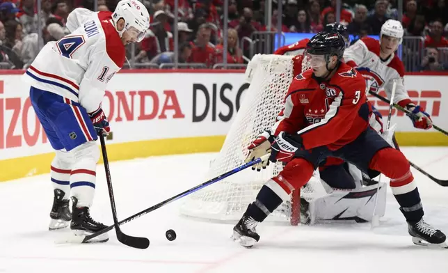 Montreal Canadiens center Nick Suzuki (14) and Washington Capitals defenseman Matt Roy (3) battle for the puck in the second period of Game 1 of a first-round NHL hockey playoff series Monday, April 21, 2025, in Washington. (AP Photo/Nick Wass)
