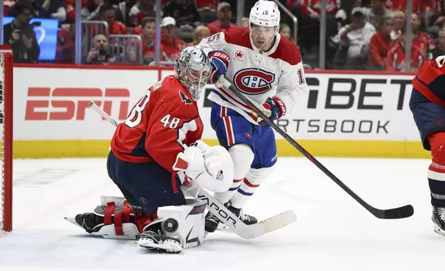Montreal Canadiens center Alex Newhook (15) and Washington Capitals goaltender Logan Thompson (48) battle for the puck in the second period of Game 1 of a first-round NHL hockey playoff series Monday, April 21, 2025, in Washington. (AP Photo/Nick Wass)