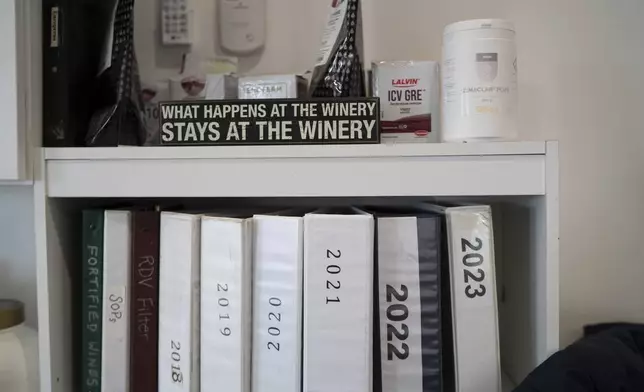 A sign that reads, "What happens at the winery stays at the winery," sits on a shelf in the head winemaker's office at Fox Run Vineyards, Friday, March 21, 2025, in Penn Yan, N.Y. (Natasha Kaiser via AP)