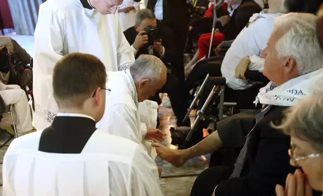 FILE - Pope Francis, center, kneels to wash the feet of a man at the Don Gnocchi Foundation Center in Rome, Thursday, April 17, 2014. (AP Photo/Riccardo De Luca, File)