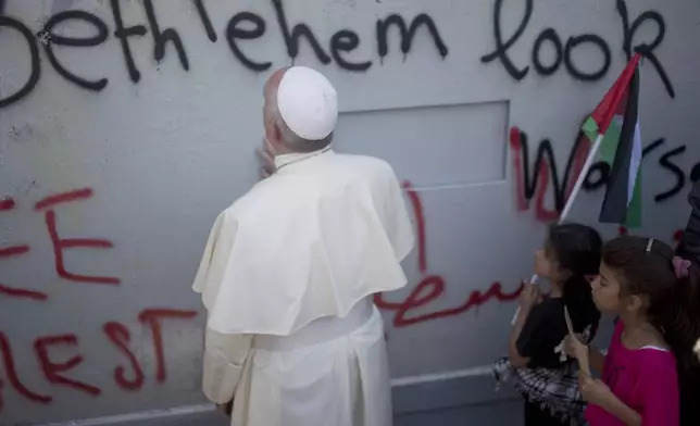 FILE - Pope Francis prays at Israel's separation barrier on his way to a mass in Manger Square next to the Church of the Nativity, traditionally believed to be the birthplace of Jesus Christ in the West Bank city of Bethlehem on Sunday, May 25, 2014. (AP Photo/Ariel Schalit, File)