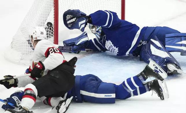 Toronto Maple Leafs goaltender Anthony Stolarz (41) dives for the loose puck on a shot by Ottawa Senators' Fabian Zetterlund (20) as Morgan Rielly (44) defends during the second period of an NHL hockey playoff game in Toronto on Tuesday, April 29, 2025. (Nathan Denette/The Canadian Press via AP)