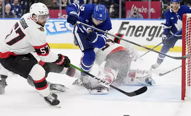 Toronto Maple Leafs' Steven Lorentz (18) falls over Ottawa Senators goaltender Linus Ullmark (35) as David Perron (57) picks up the loose puck during the second period of an NHL hockey playoff game in Toronto on Tuesday, April 29, 2025. (Frank Gunn/The Canadian Press via AP)